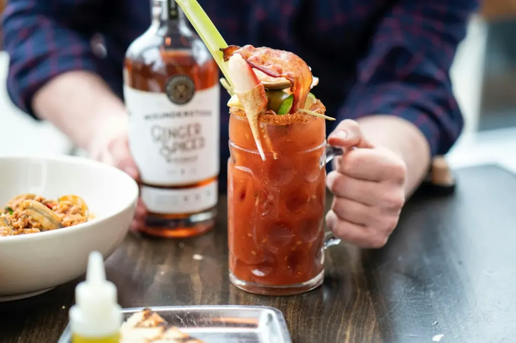 A tall Bloody Mary loaded with celery and garnishes on a bar table