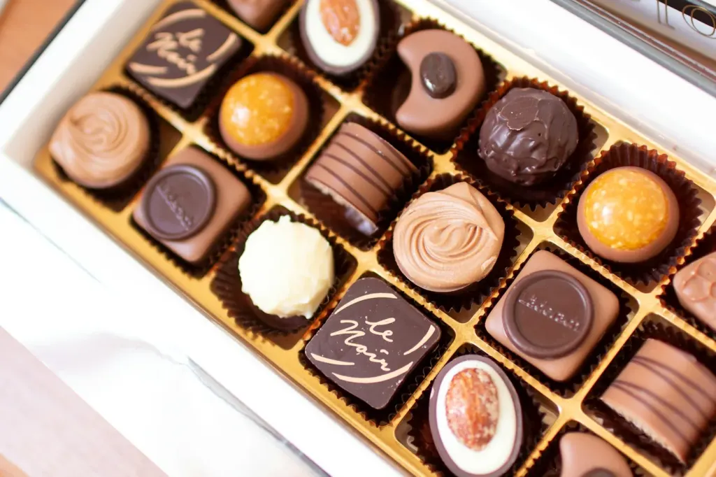 An open box of filled chocolates in paper cases