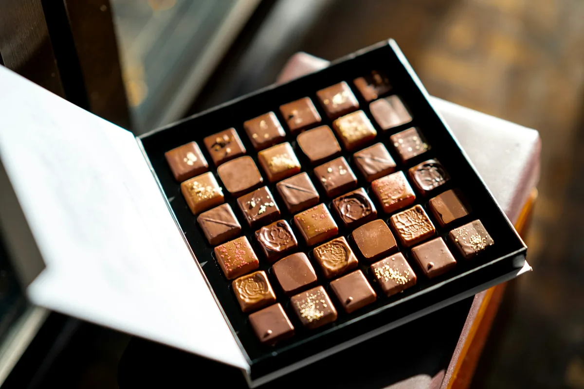 A large flat box of filled chocolates with the lid lifted