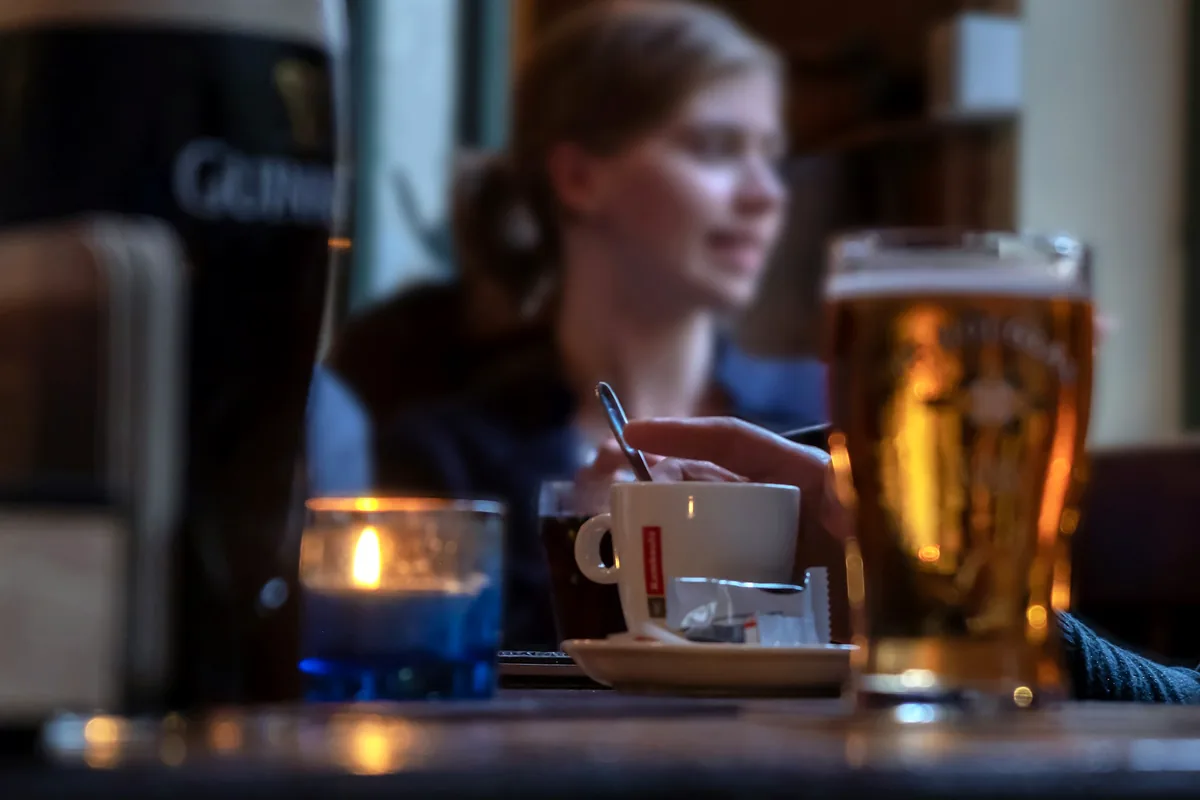 A woman with a glass of beer at a table in a Belgian cafe