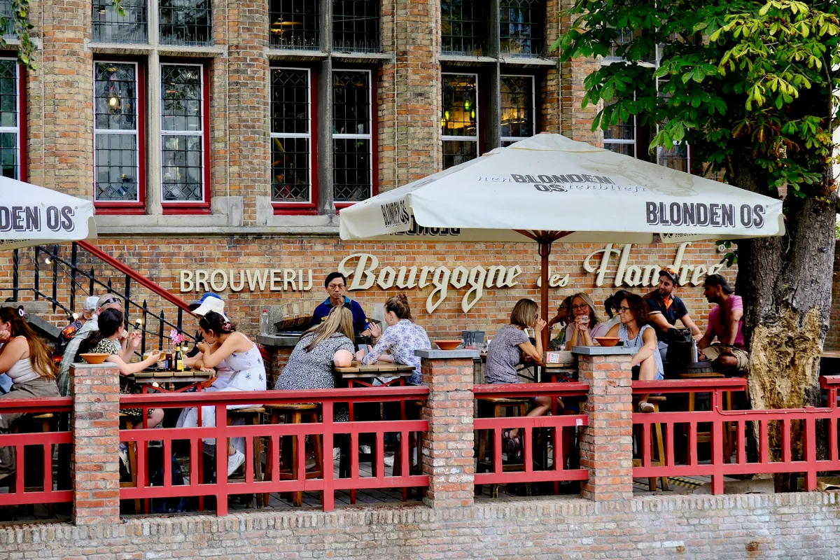 A brewery terrace with parasols beside a canal in Bruges