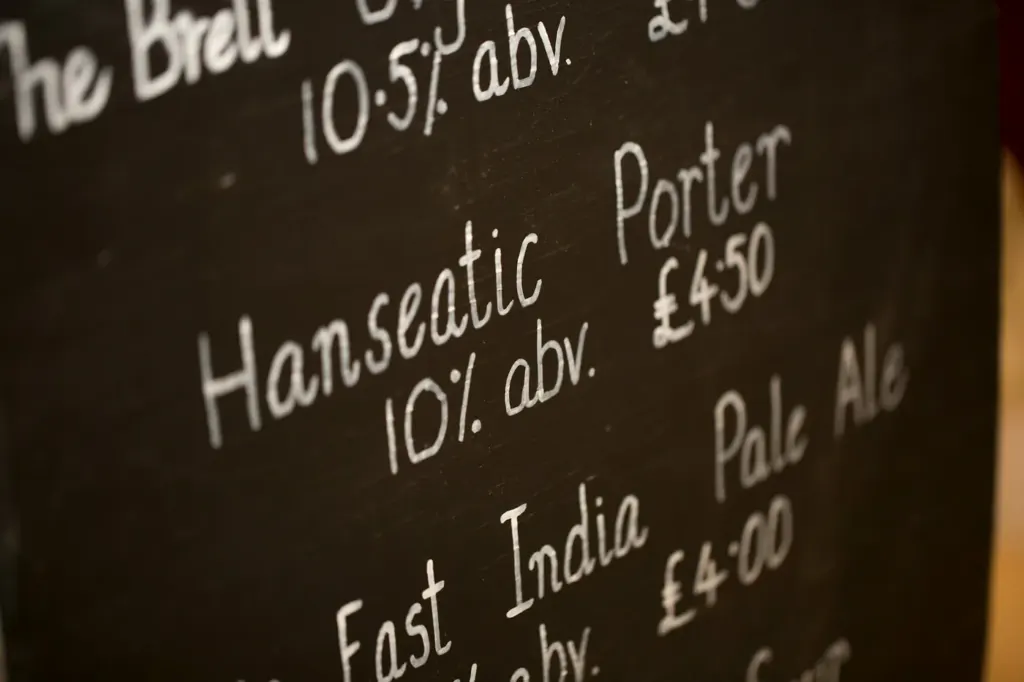 A chalkboard listing beers with their strengths and prices