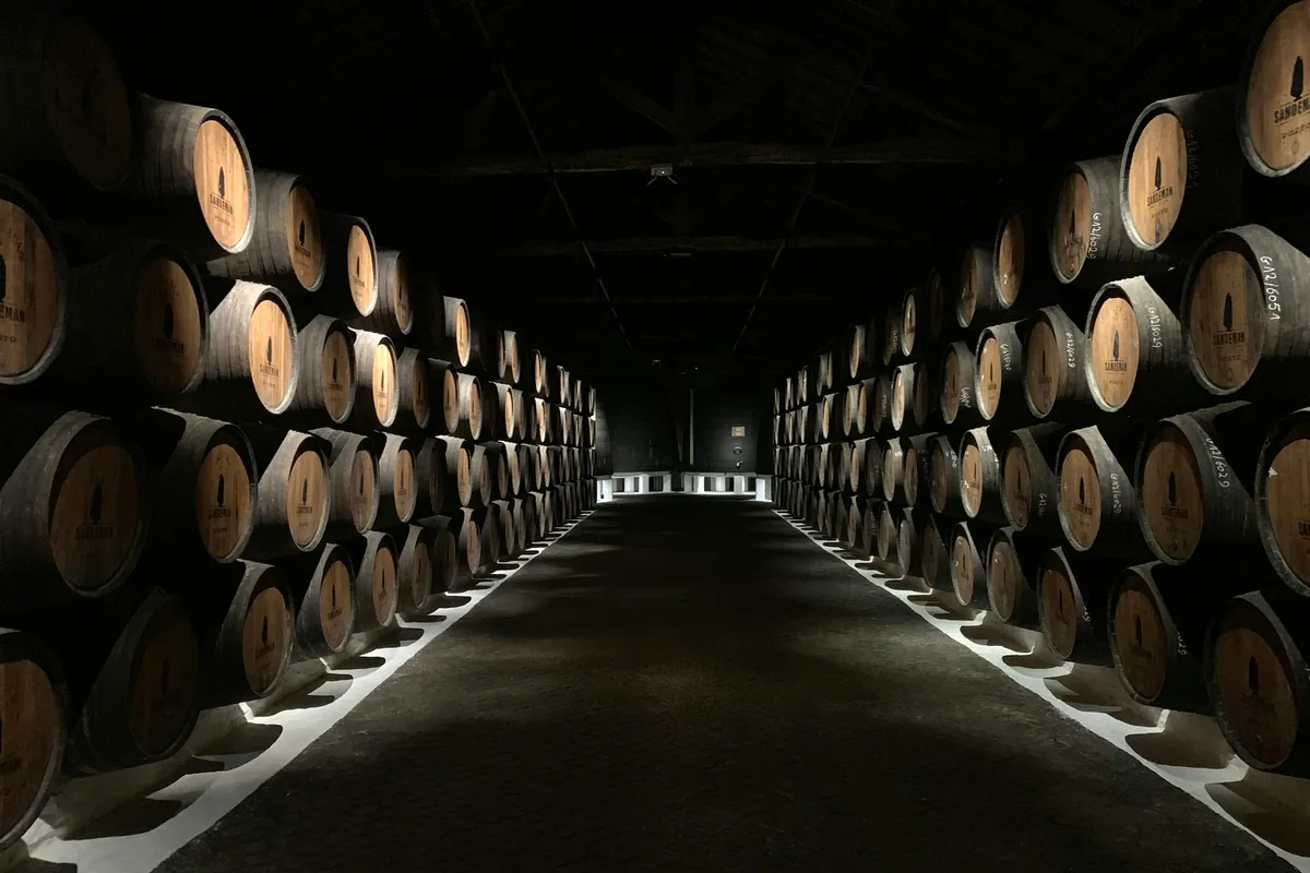 A long dim hall lined floor to ceiling with stacked barrels
