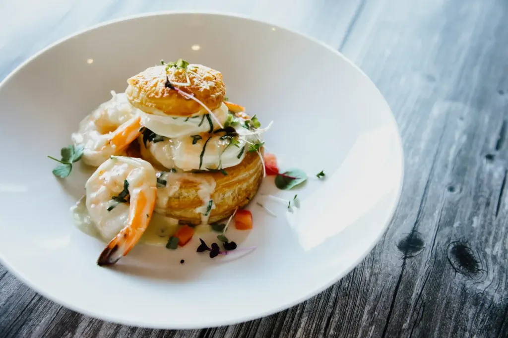 A puff pastry case filled with seafood and cream sauce on a white plate
