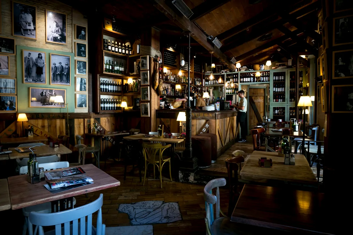 A warm wood-panelled bar room hung with pictures and lined with bottles