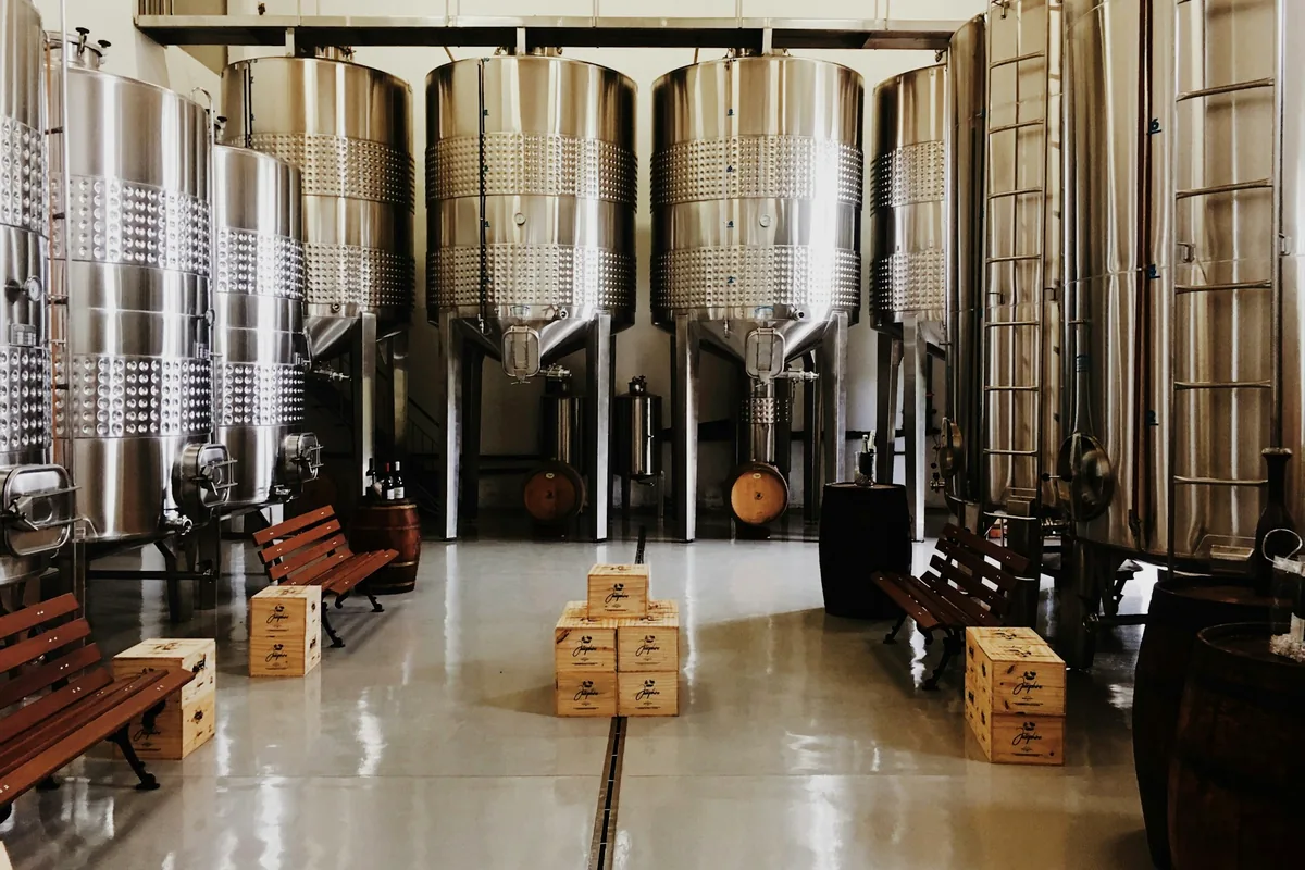 A line of tall conical stainless steel fermenting vessels in a brewery
