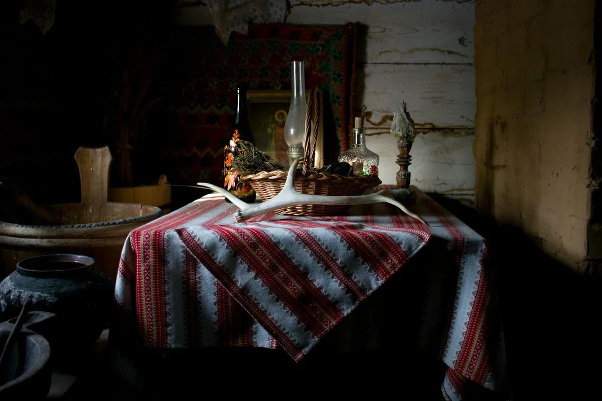 A dim rural room with a striped tablecloth and an oil lamp on the table