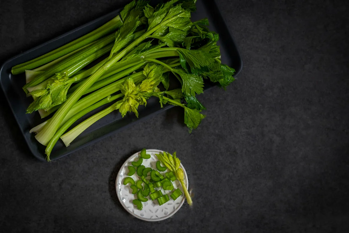 Trimmed celery stalks on a dark tray beside a dish of salt