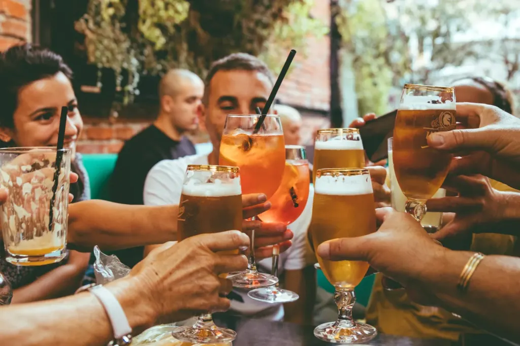 A group around an outdoor table raising glasses of beer together