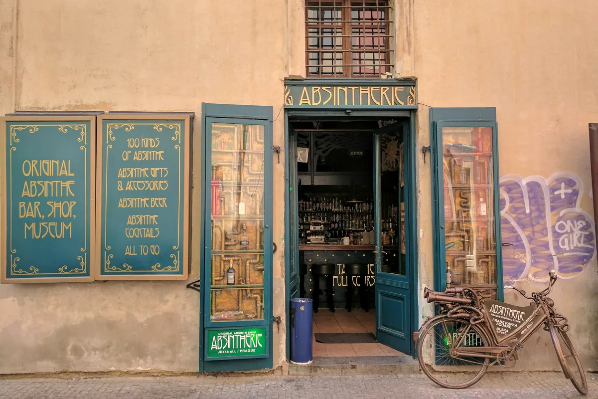 The blue-painted shopfront of an absinthe bar, shop and museum with a bicycle outside