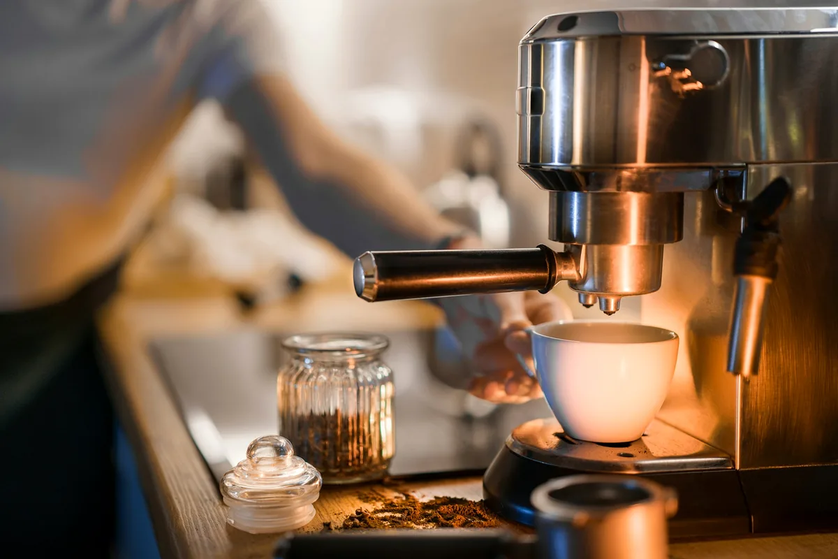 A barista working an espresso machine with a cup beneath the group head