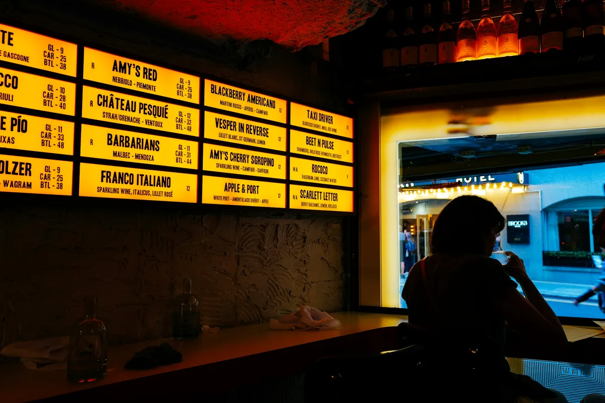 A lit menu board mounted above a bar counter