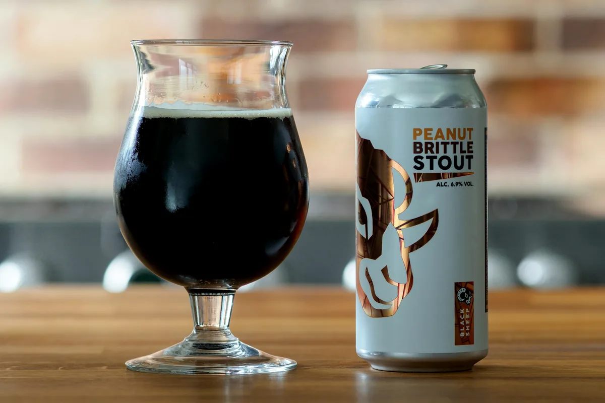 A glass of beer on a wooden surface against a blurred background