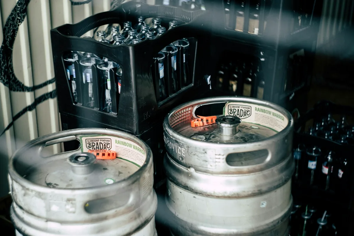 Two stainless steel beer kegs beside crates of glassware