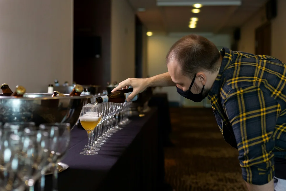 A long table being set with rows of small tasting glasses for a beer tasting
