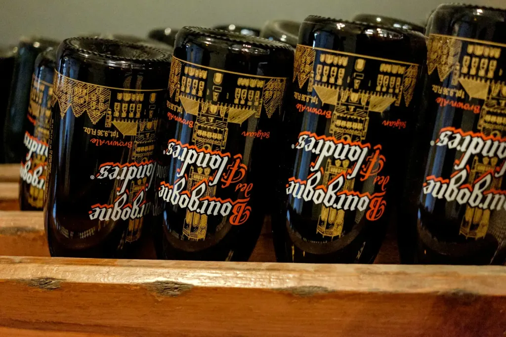 Rows of Belgian beer bottles standing on a wooden shelf