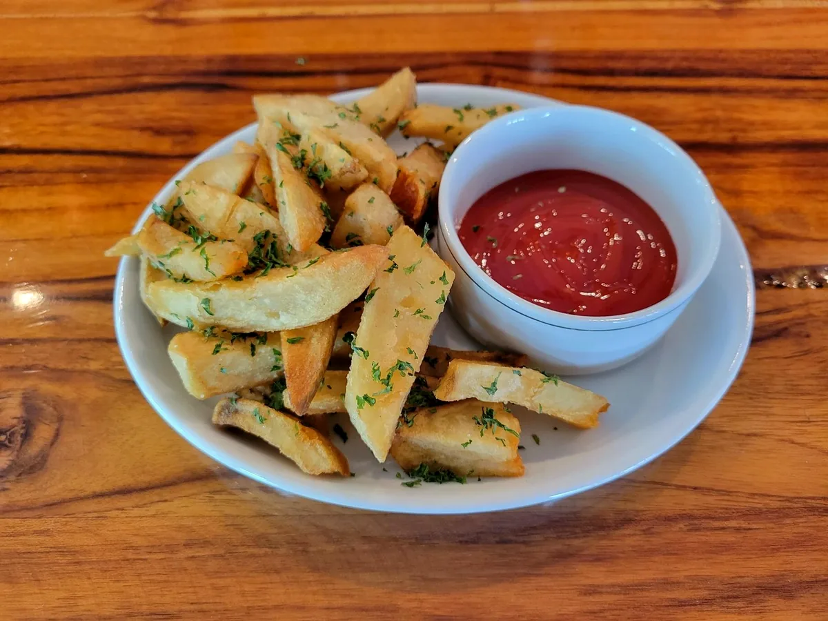 Hand-cut Belgian frites with a dish of dipping sauce on a white plate