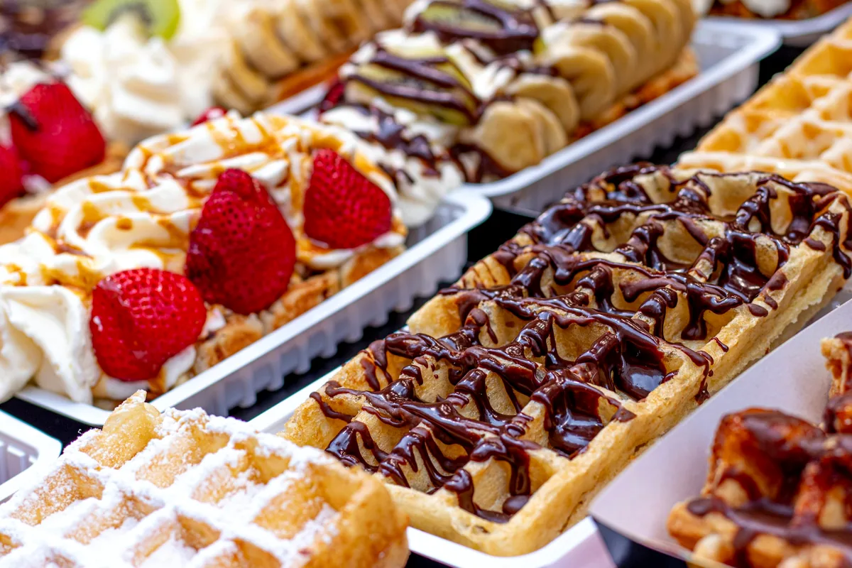 A display of Belgian waffles topped with cream, chocolate and strawberries