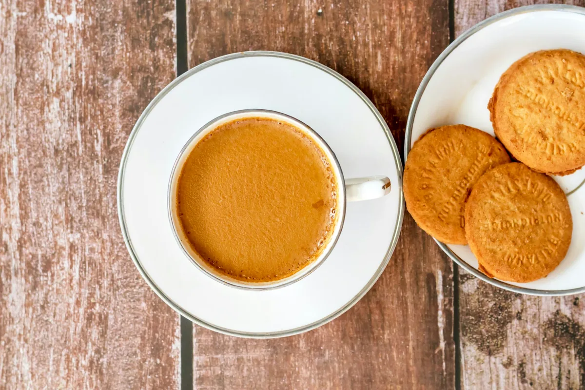 An overhead view of a cup of coffee beside a bowl of round biscuits