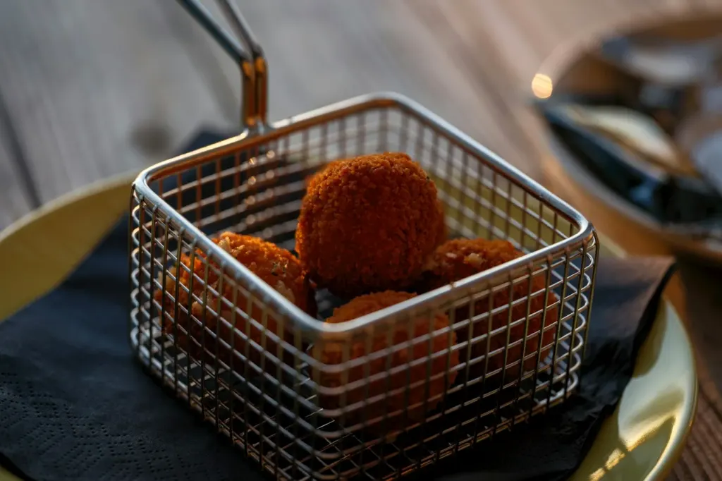 Crisp golden bitterballen served in a small wire fry basket
