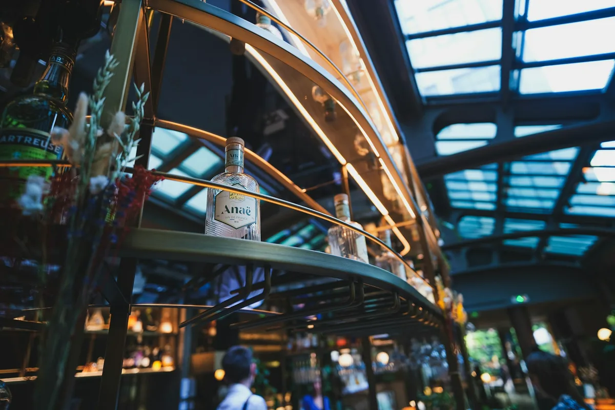 A single bottle standing on a lit shelf behind a bar