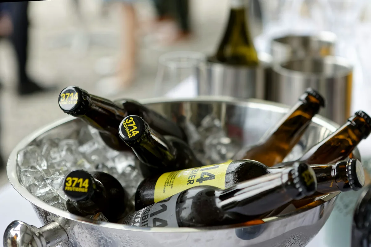 Brown and green beer bottles packed into a metal bucket of ice