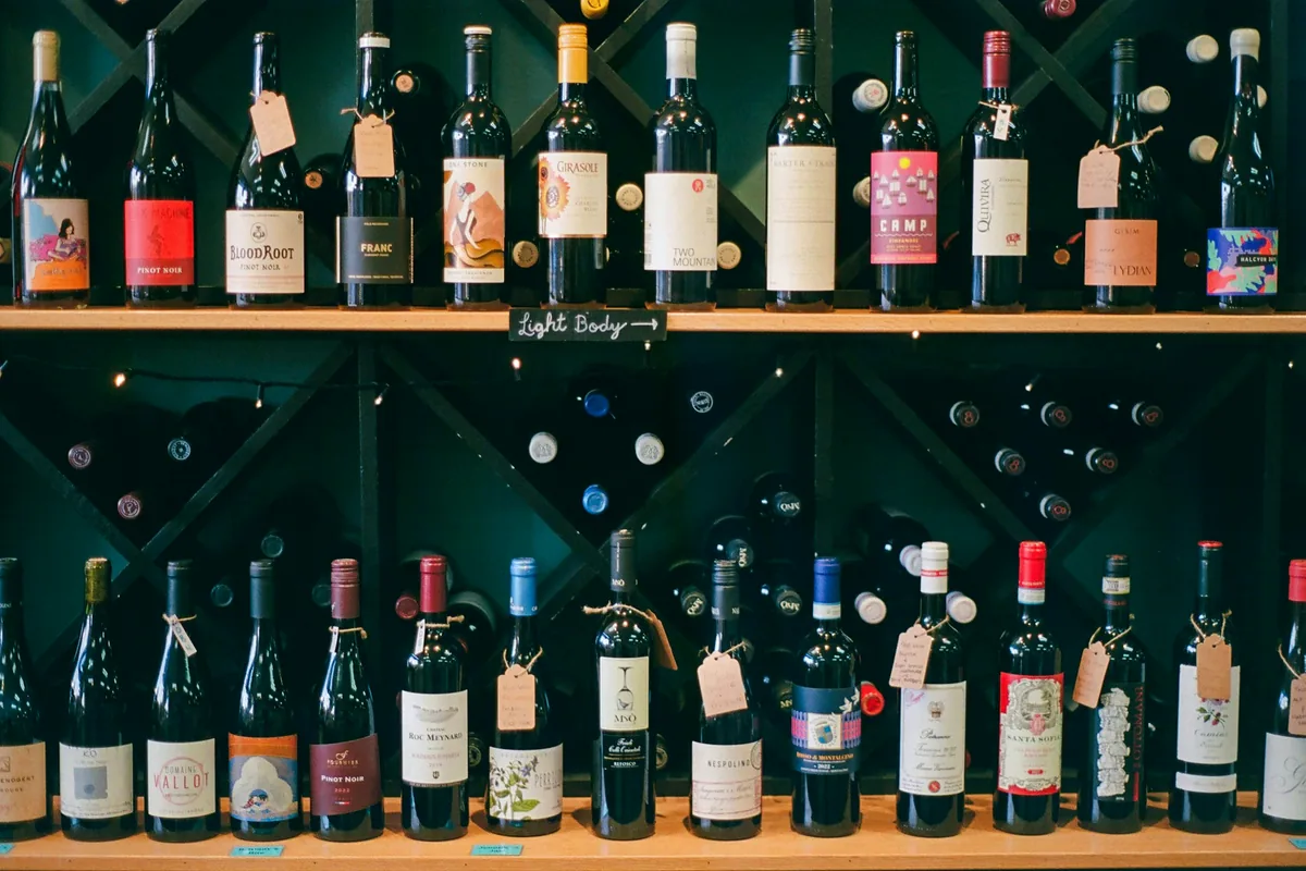 An assortment of bottles standing in rows on shop shelving