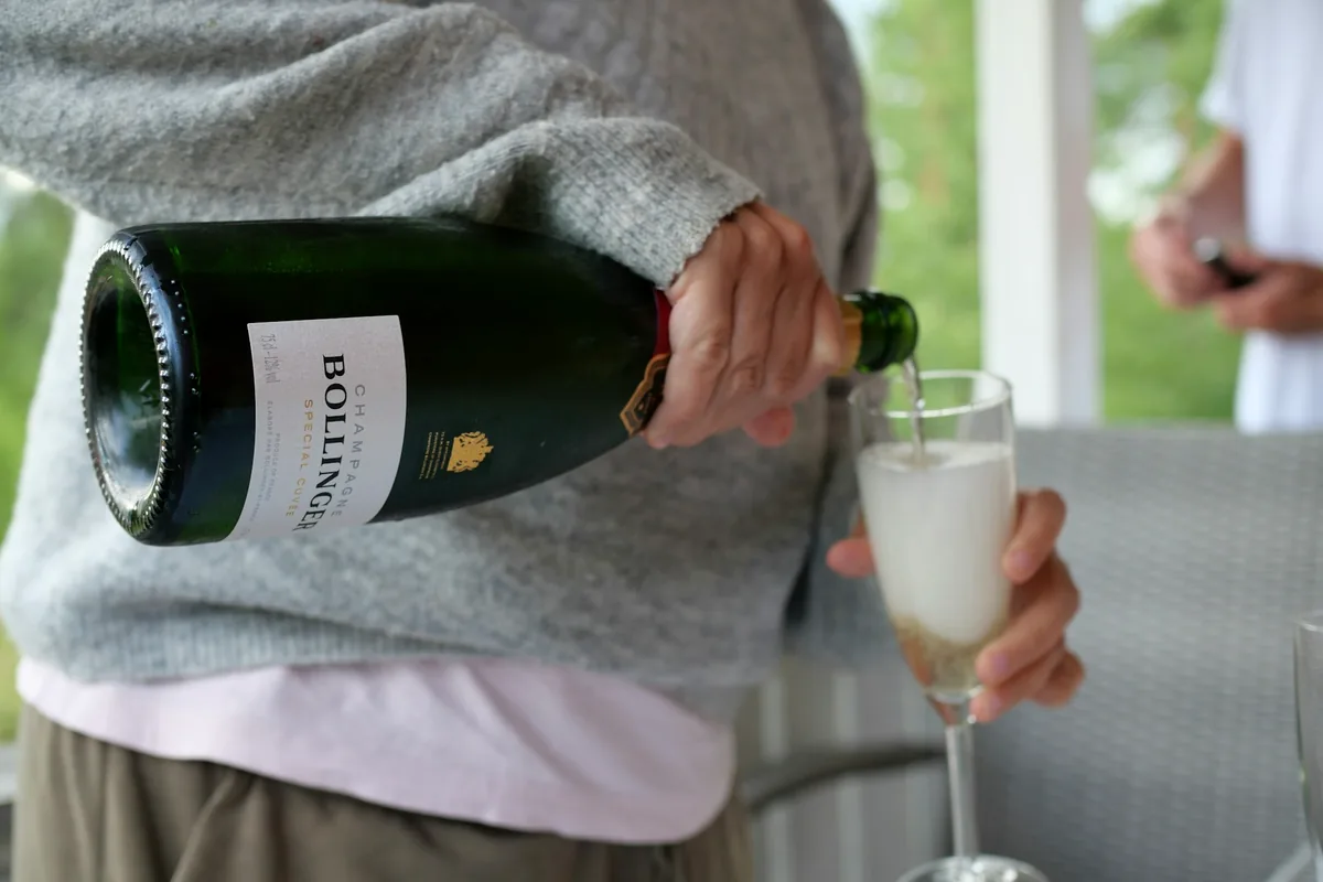 A bottle of sparkling wine being poured into a tall flute