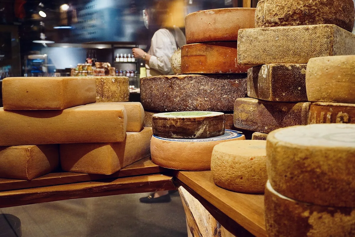 A cheese shop counter stacked with wheels and rounds of cheese