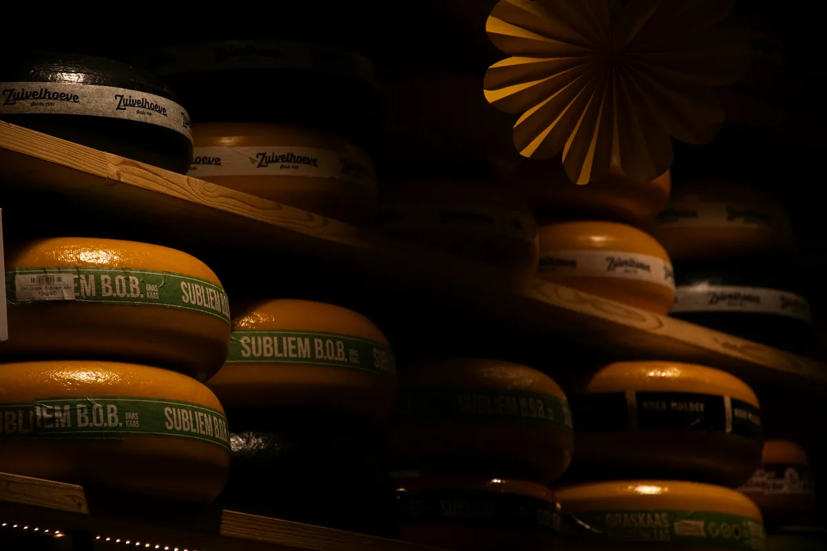 Rows of waxed cheese wheels stacked on dark wooden shelves