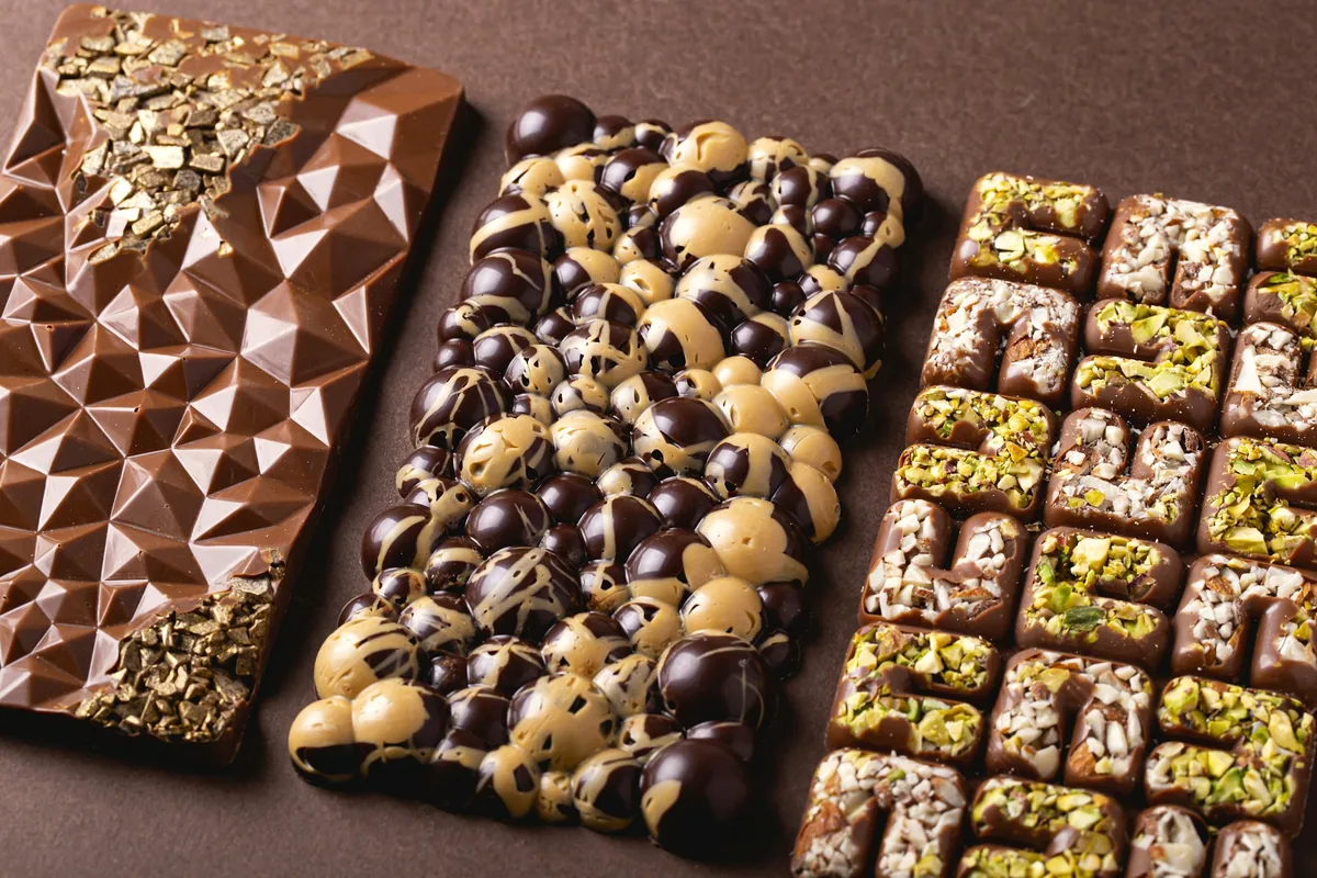 Rows of moulded and dusted chocolates arranged on a white surface