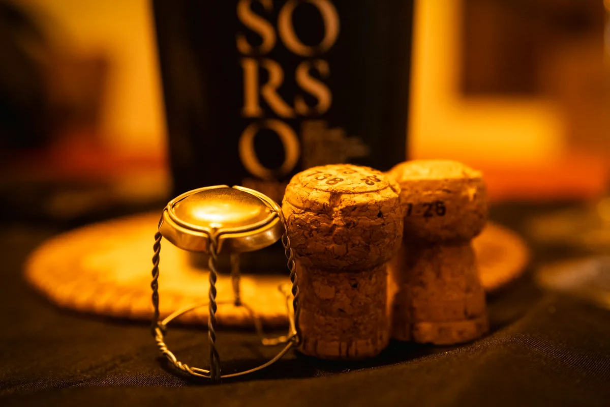 Two sparkling wine corks and a wire muselet cage on a table
