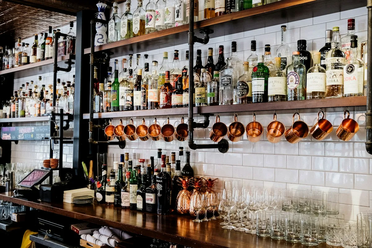 A craft cocktail bar with bottles arrayed on shelves behind the counter