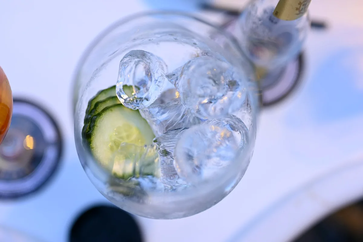 A stemmed balloon glass filled with ice and cucumber slices