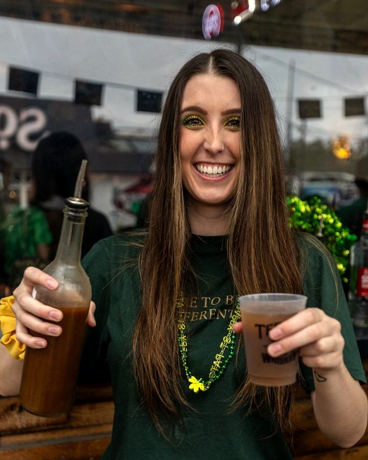 A bartender at Meyboom Brasserie holding a bottle and a drink behind the bar