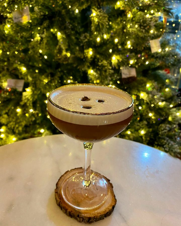 An espresso martini on the marble bar top in front of the Christmas tree at Meyboom Brasserie