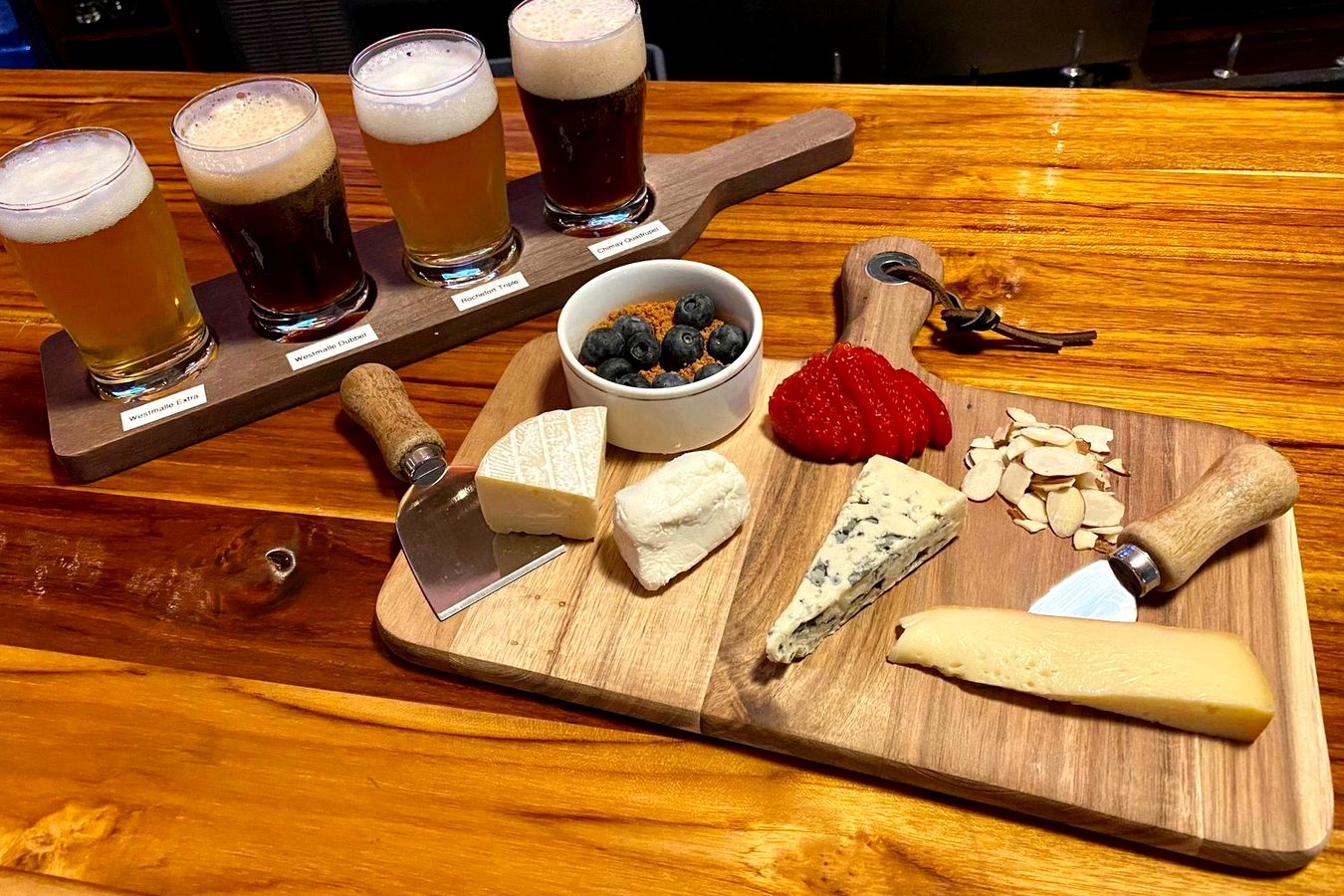 A flight of Belgian beers beside a cheese board at Meyboom Brasserie