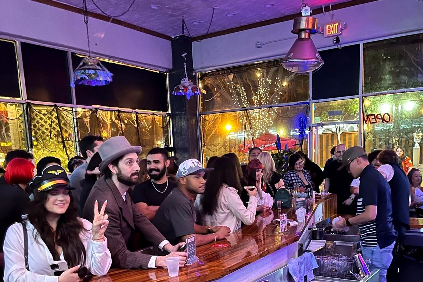 Guests along the bar at Meyboom Brasserie under the purple ceiling lights