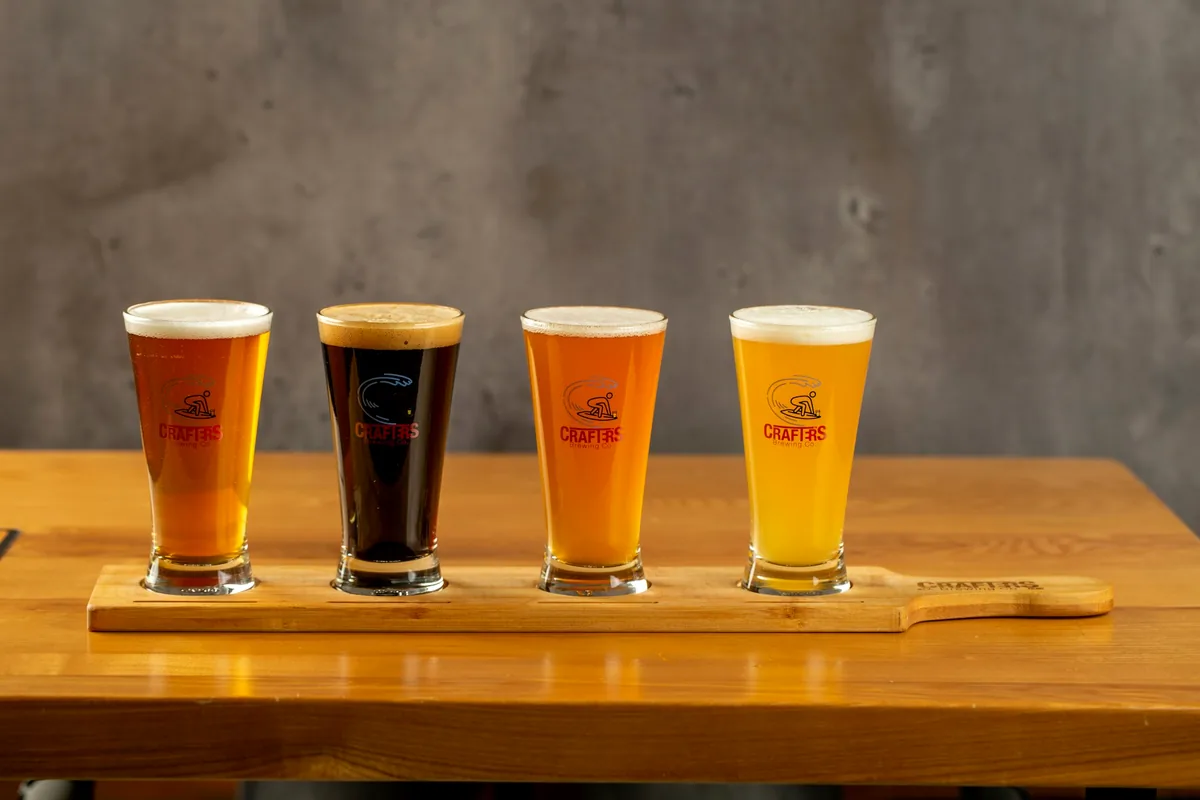 A four-glass tasting flight on a wooden paddle