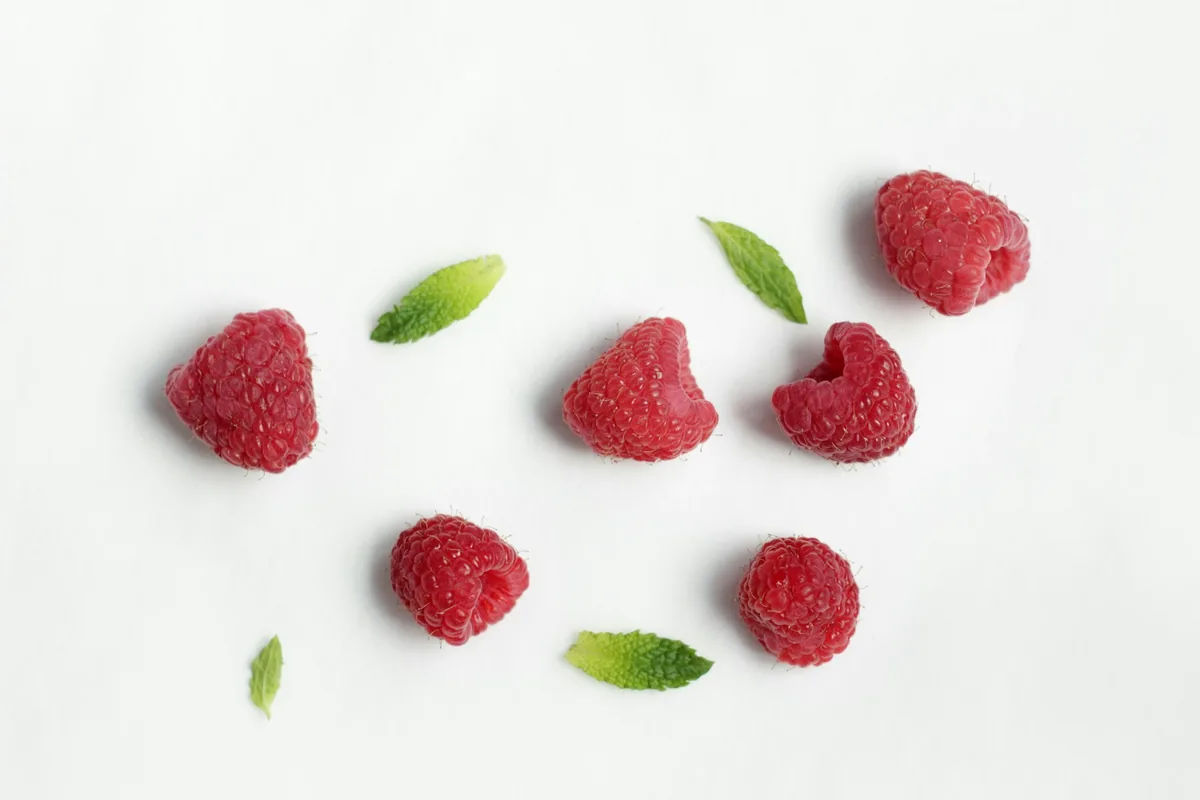 Fresh raspberries scattered on a white surface