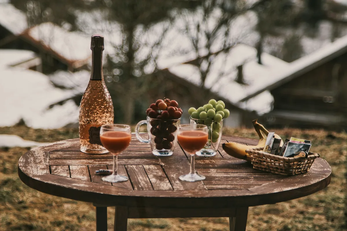 Two glasses and a bottle on a weathered outdoor wooden table