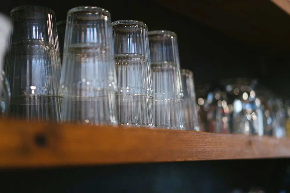 Rows of beer glasses stacked upside down on a wooden shelf