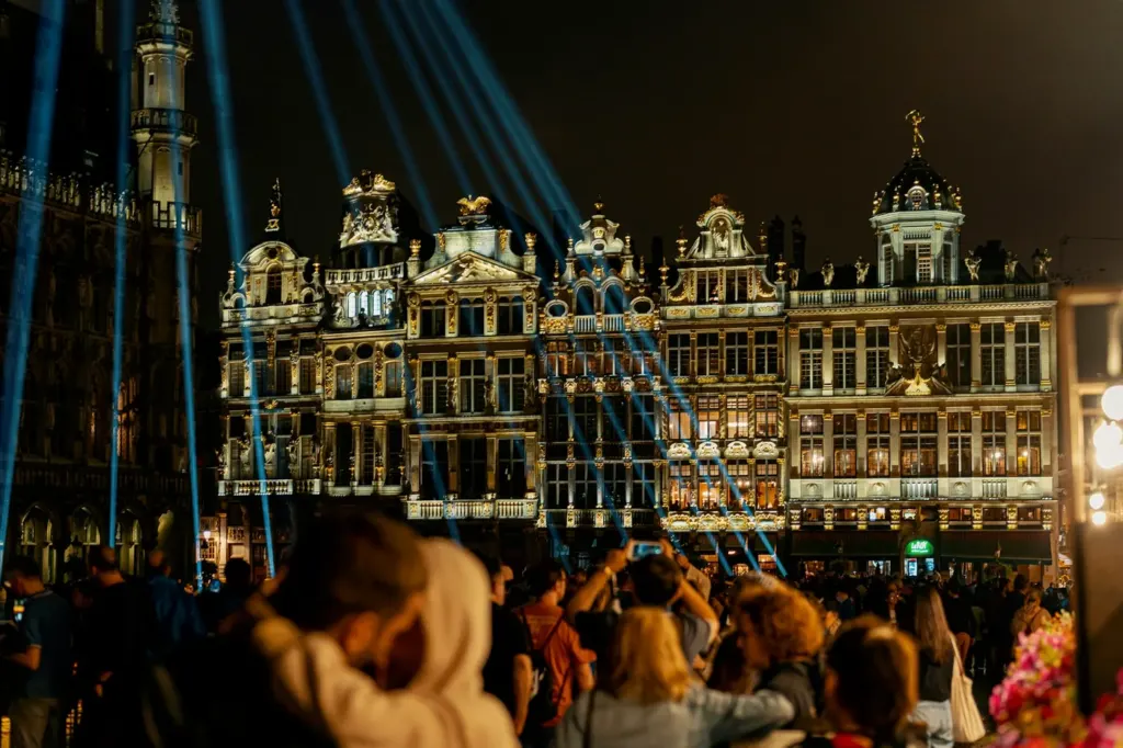 A crowd filling the Grand-Place in Brussels at night beneath the lit guildhalls