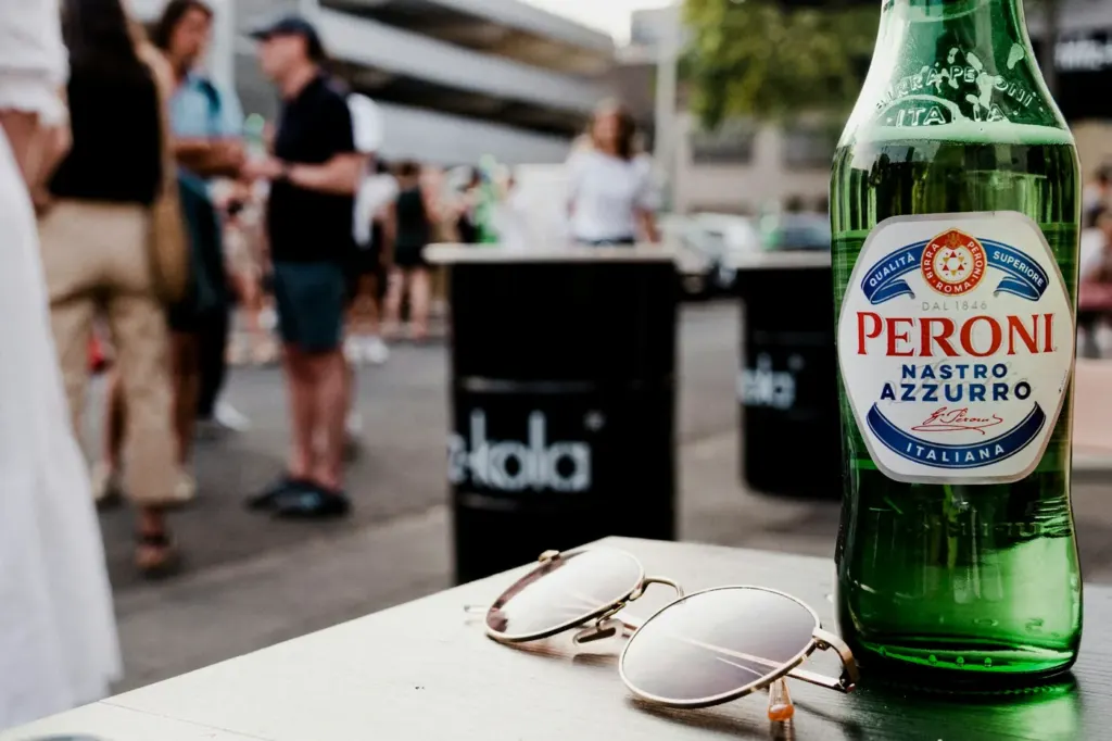 A green beer bottle standing on an outdoor table in bright sunlight