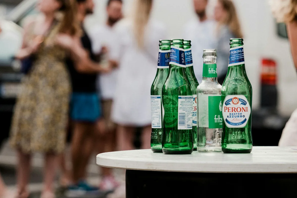 Several green beer bottles standing on a white outdoor table