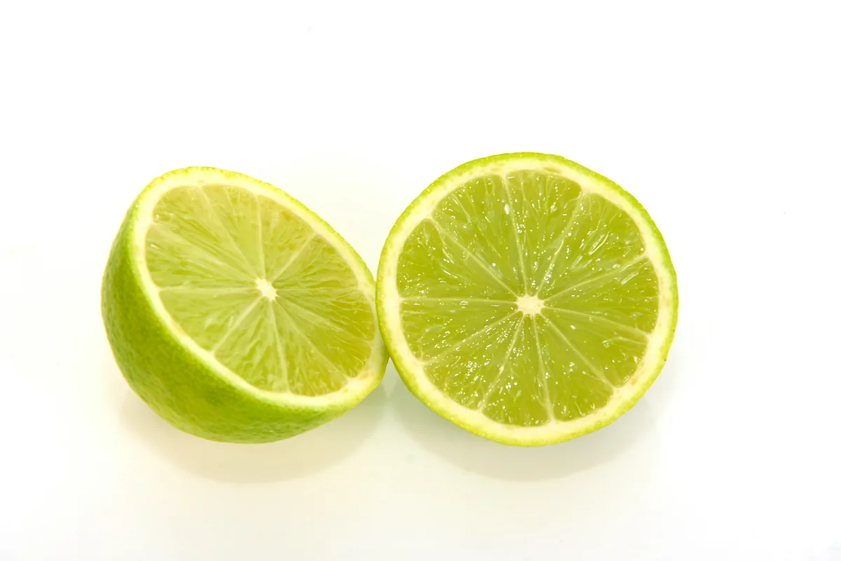 Two halves of a fresh lime on a white surface