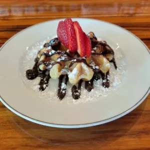A Liege waffle with chocolate sauce, strawberries and powdered sugar