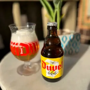 A Duvel bottle beside a tulip glass on a marble table
