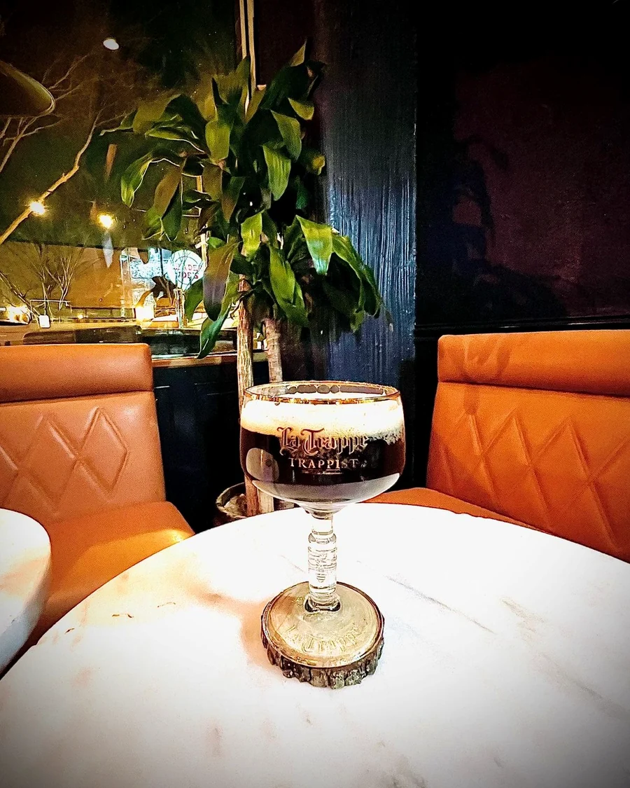A dark Trappist ale in a La Trappe glass on a marble table