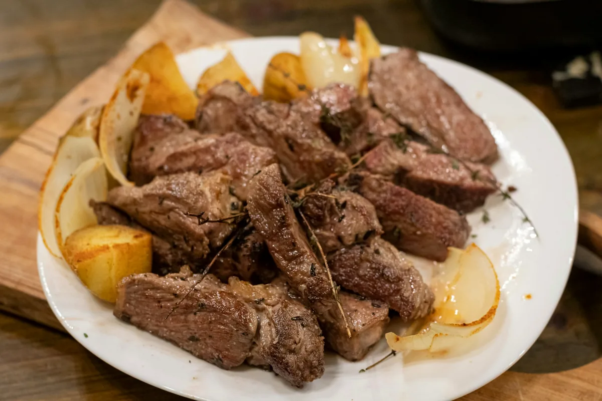 Slices of braised beef with potatoes on a white plate
